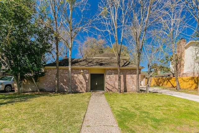 view of front facade featuring brick siding, a front yard, and fence