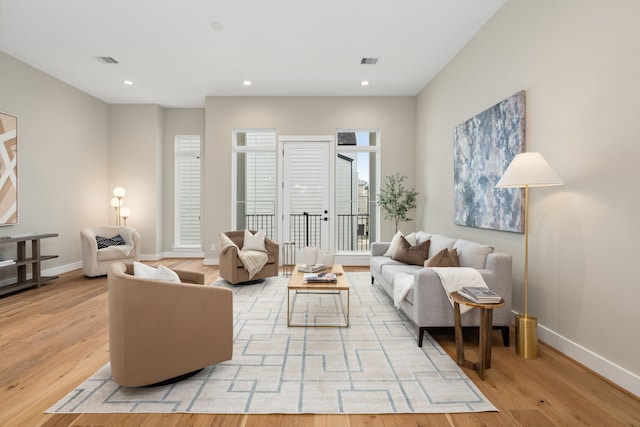 living room with recessed lighting, visible vents, baseboards, and light wood finished floors