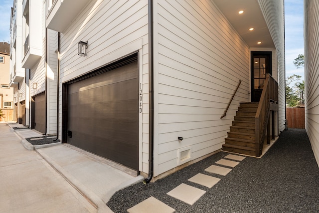 garage with concrete driveway and fence