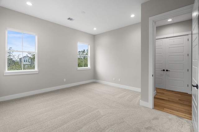 unfurnished room with baseboards, visible vents, plenty of natural light, and light carpet