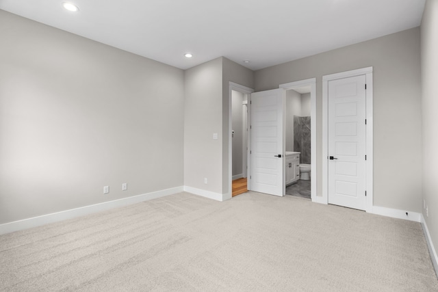 unfurnished bedroom with connected bathroom, recessed lighting, baseboards, and light carpet