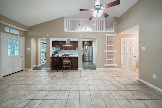 kitchen with stainless steel appliances, a breakfast bar area, light countertops, light tile patterned floors, and dark brown cabinets