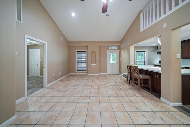 entrance foyer with light tile patterned floors, a ceiling fan, baseboards, and high vaulted ceiling