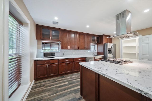 kitchen with light stone countertops, visible vents, appliances with stainless steel finishes, backsplash, and island range hood