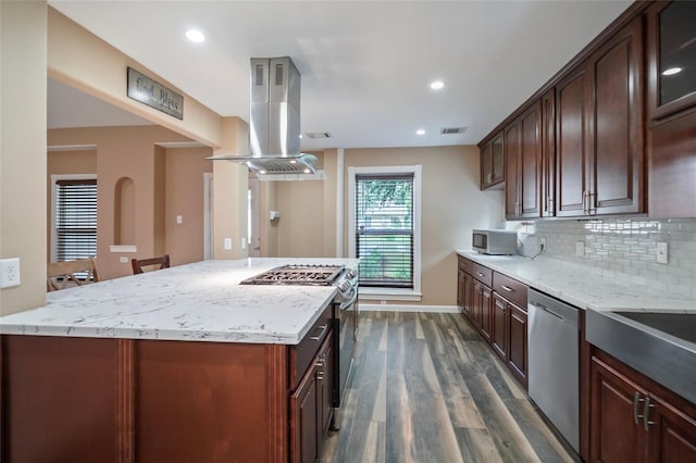 kitchen with tasteful backsplash, visible vents, light stone countertops, island range hood, and stainless steel appliances