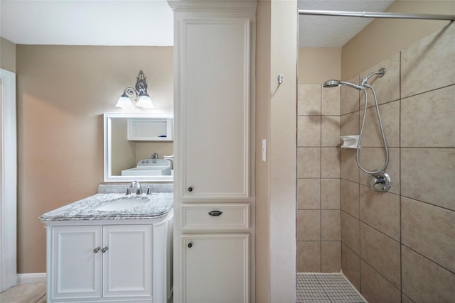 full bathroom featuring washer / dryer, tiled shower, and vanity