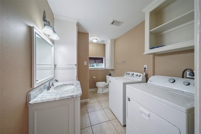 washroom featuring visible vents, washer and clothes dryer, light tile patterned floors, laundry area, and a sink