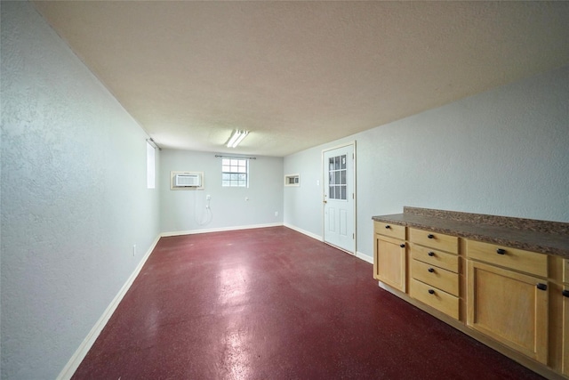 spare room featuring concrete floors, a wall mounted AC, and baseboards