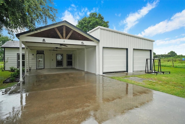 view of front of property with a carport, a front yard, a detached garage, and ceiling fan