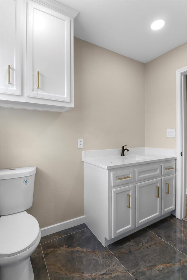 bathroom with baseboards, toilet, and vanity