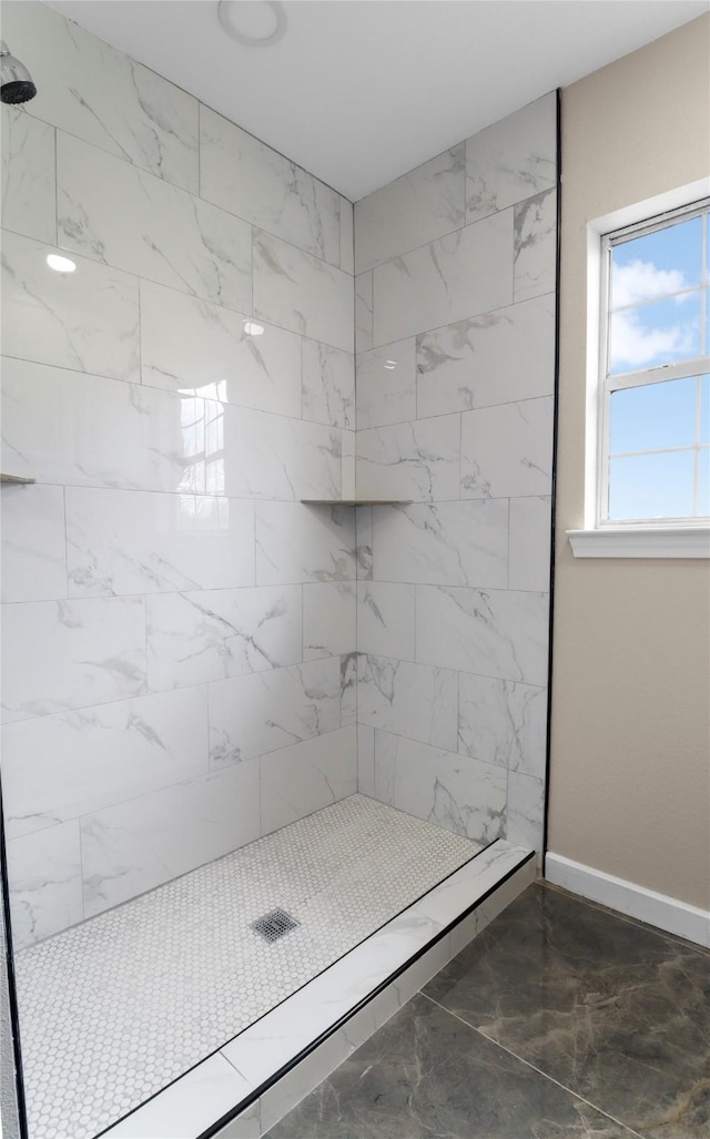 full bathroom featuring tiled shower and baseboards