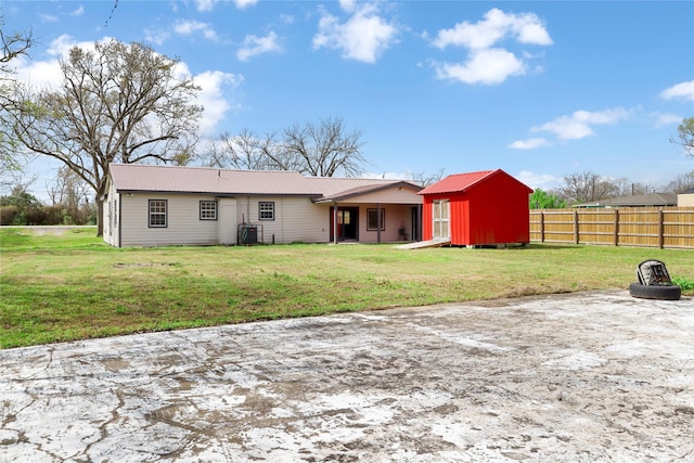 back of property featuring a lawn, metal roof, and fence