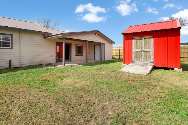 back of house with a storage unit, an outbuilding, a fenced backyard, and a lawn