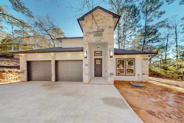 view of front of home featuring stone siding, driveway, a shingled roof, and a garage