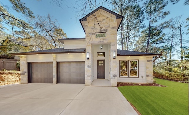 view of front of house with driveway, stone siding, roof with shingles, a front yard, and an attached garage