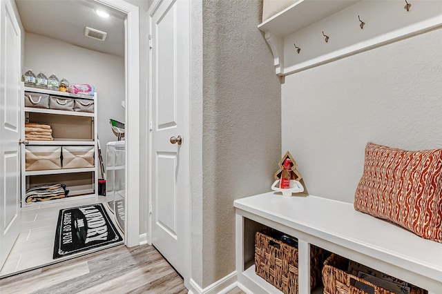 mudroom with visible vents, wood finished floors, and a textured wall