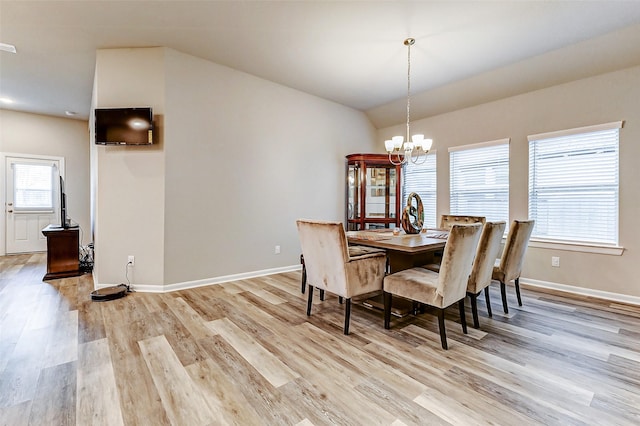 dining space featuring a chandelier, light wood-type flooring, baseboards, and vaulted ceiling