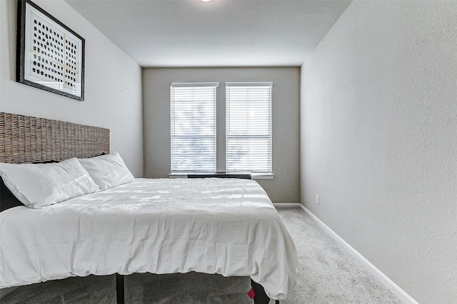 bedroom featuring baseboards, carpet, and a textured wall