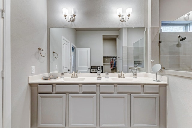 full bath with a tile shower, double vanity, a closet, and a sink