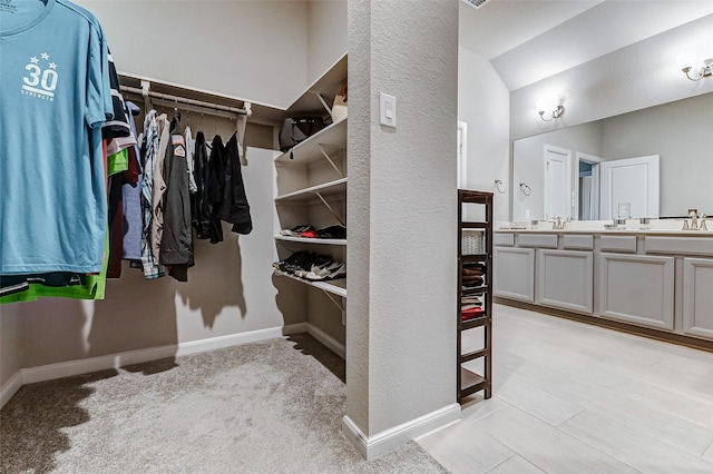 spacious closet featuring lofted ceiling, light colored carpet, and a sink