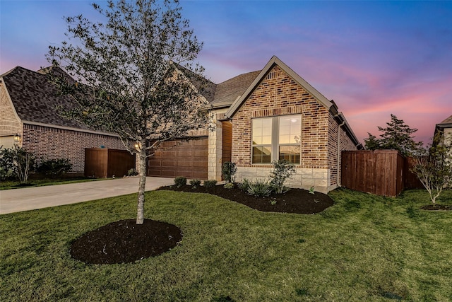 view of front of property with concrete driveway, fence, brick siding, and a lawn