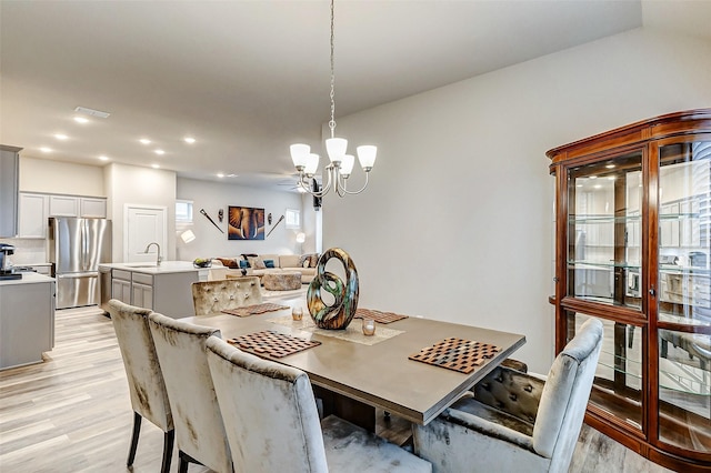 dining space featuring light wood finished floors, recessed lighting, and an inviting chandelier