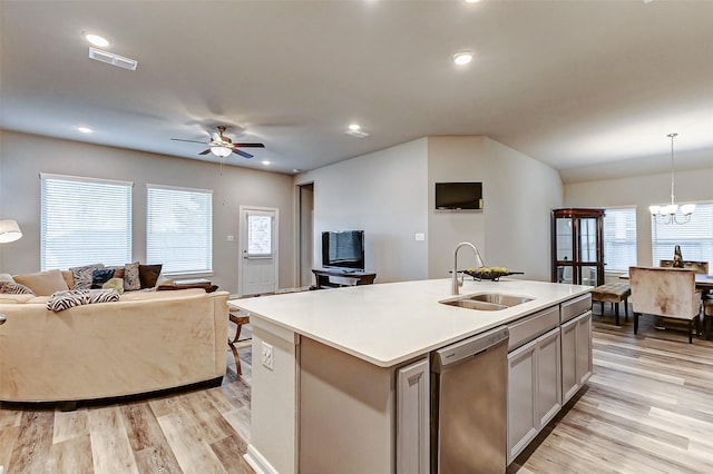 kitchen featuring open floor plan, light countertops, light wood-type flooring, stainless steel dishwasher, and a sink