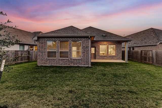 rear view of house with a yard, a fenced backyard, and brick siding