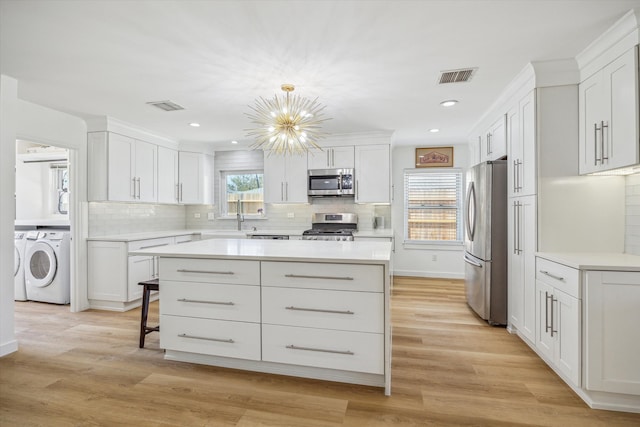 kitchen with visible vents, a kitchen island, light countertops, appliances with stainless steel finishes, and independent washer and dryer