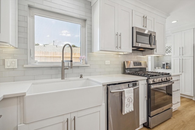 kitchen featuring decorative backsplash, white cabinets, a sink, and stainless steel appliances