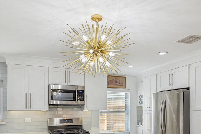 kitchen featuring visible vents, appliances with stainless steel finishes, white cabinetry, a notable chandelier, and backsplash