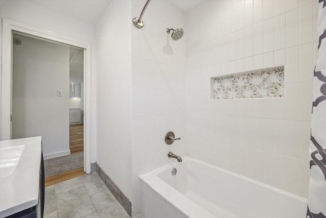 bathroom with vanity, bathing tub / shower combination, and baseboards