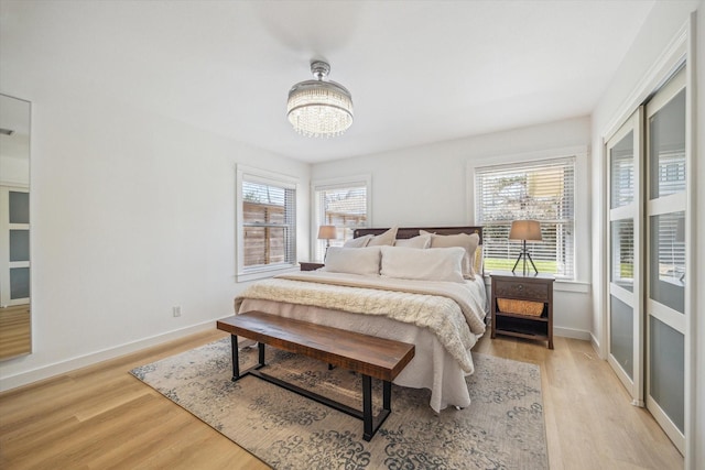 bedroom featuring baseboards, a chandelier, and light wood finished floors