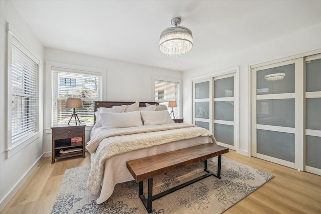 bedroom with a chandelier, multiple windows, baseboards, and light wood-style flooring