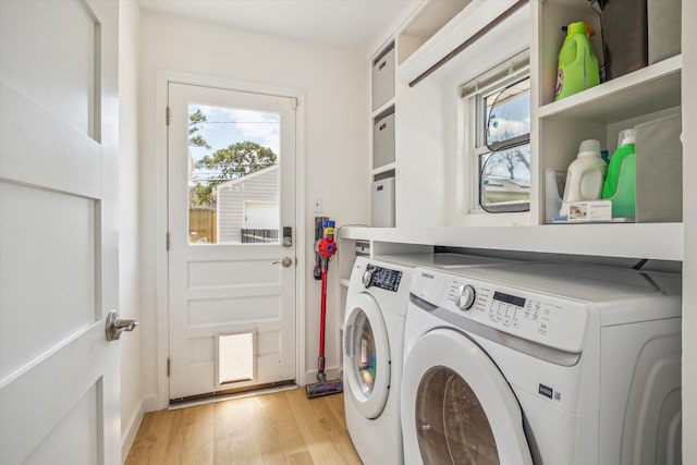 clothes washing area with washing machine and dryer, laundry area, and light wood finished floors