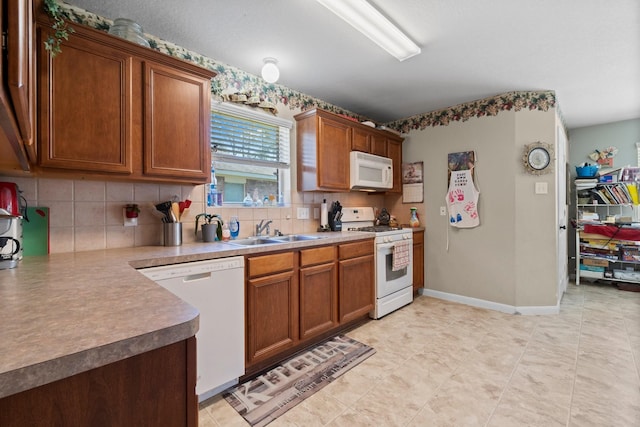 kitchen featuring a sink, baseboards, white appliances, and backsplash