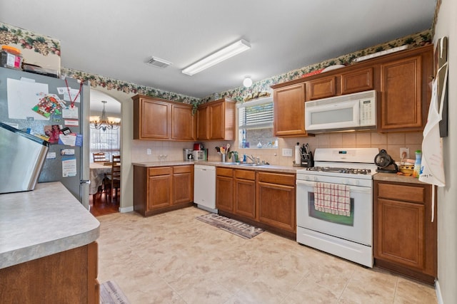 kitchen featuring visible vents, white appliances, brown cabinets, and light countertops