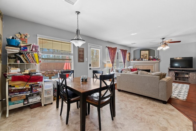 dining space with ceiling fan, tile patterned flooring, and a tile fireplace