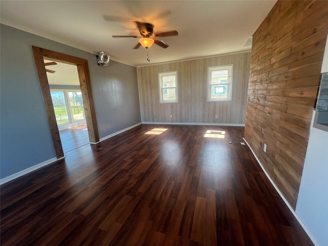 spare room with a wealth of natural light, dark wood-type flooring, and ornamental molding