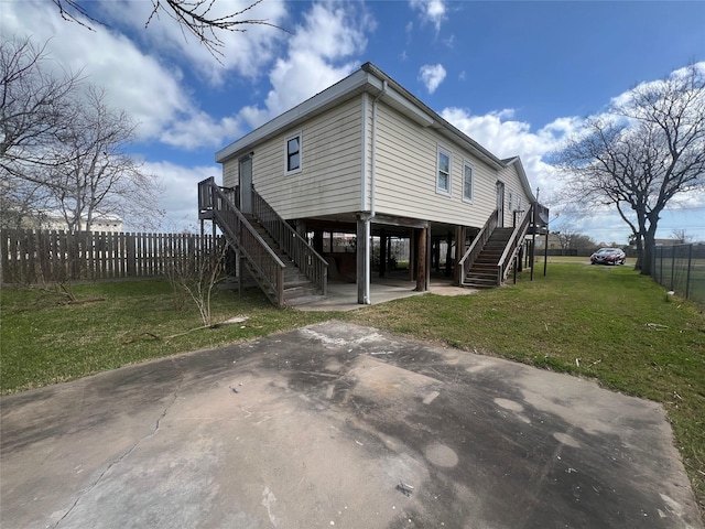 exterior space with driveway, fence, a yard, a carport, and stairs