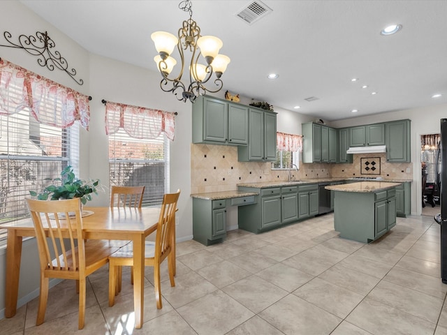 kitchen featuring tasteful backsplash, visible vents, a kitchen island, green cabinetry, and a sink