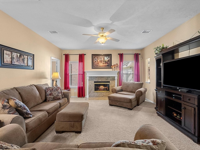 living area featuring a premium fireplace, light carpet, visible vents, and ceiling fan