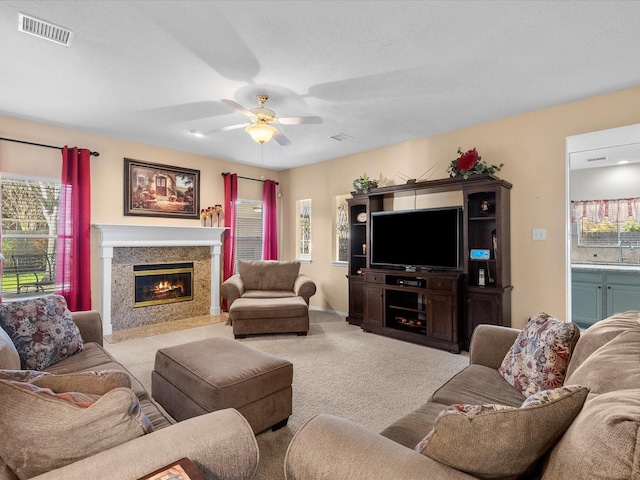 carpeted living room with visible vents, a sink, a ceiling fan, and a premium fireplace