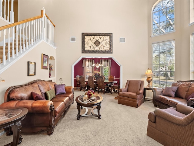 living area featuring stairs, a towering ceiling, visible vents, and carpet floors