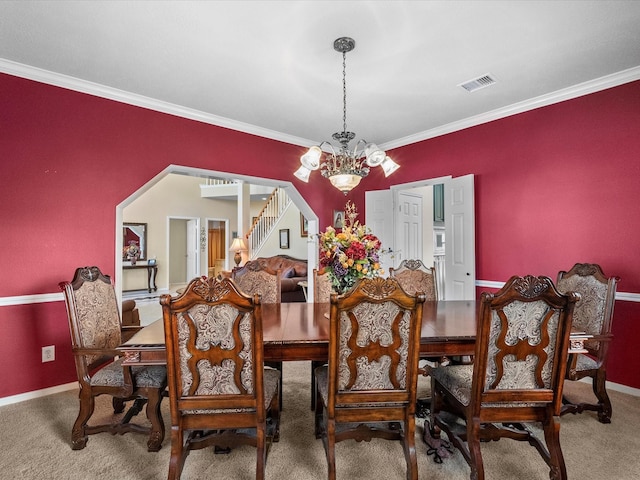 carpeted dining space featuring visible vents, a notable chandelier, ornamental molding, arched walkways, and stairs