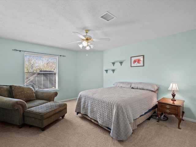 bedroom with visible vents, light colored carpet, a textured ceiling, and baseboards