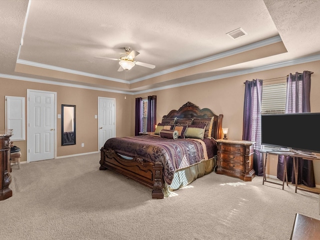 carpeted bedroom with visible vents, ceiling fan, crown molding, a textured ceiling, and a raised ceiling