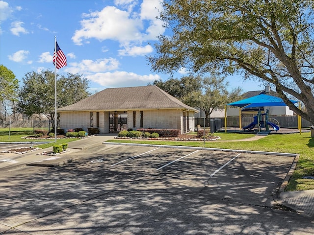 exterior space featuring a front yard, fence, playground community, and uncovered parking