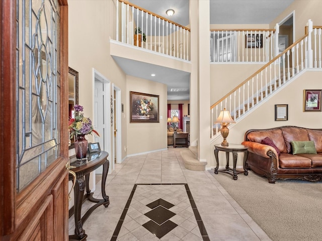 foyer featuring stairs, light tile patterned flooring, baseboards, and a towering ceiling