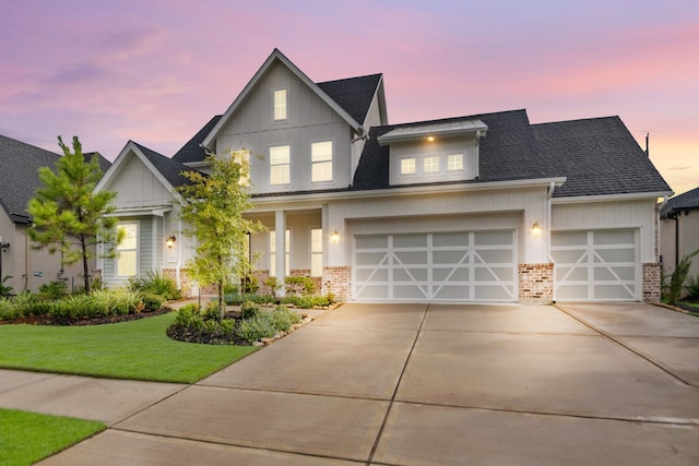 view of front facade featuring driveway, a yard, brick siding, a garage, and board and batten siding